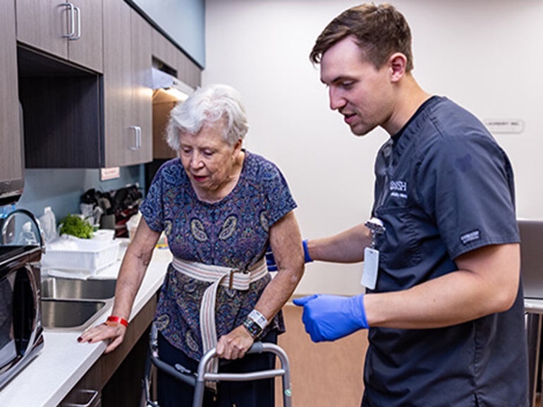 A male and his physical therapist work with an interactive screen to increase strength and cognitive ability after a brain injury.