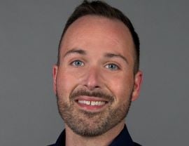 Justin King, RUSH Specialty Hospital Director of Business Development, smiles at the camera in front of a gray backdrop.